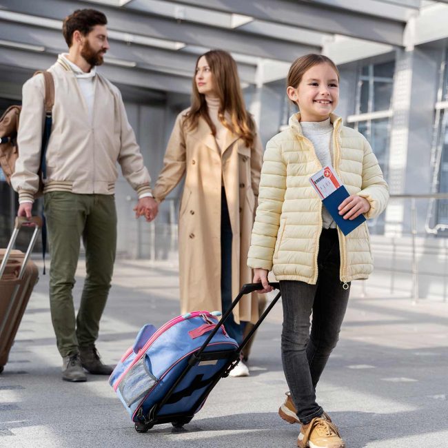 family travelling smiling small girl pulling her suitcase